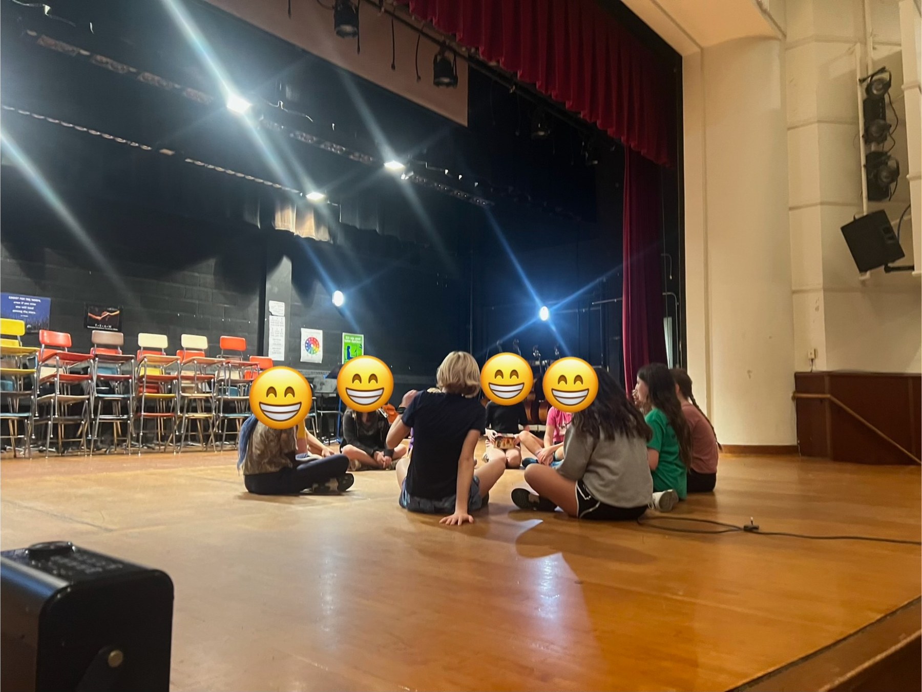 Theater club students sitting together on stage